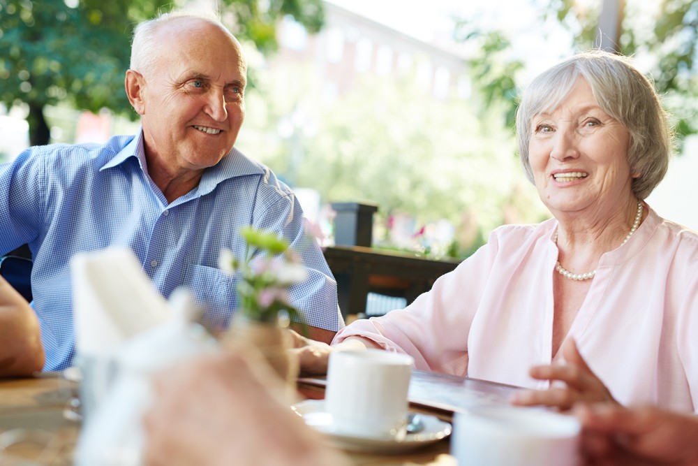 Senior adult couple at an outdoor cafe smiling and talking